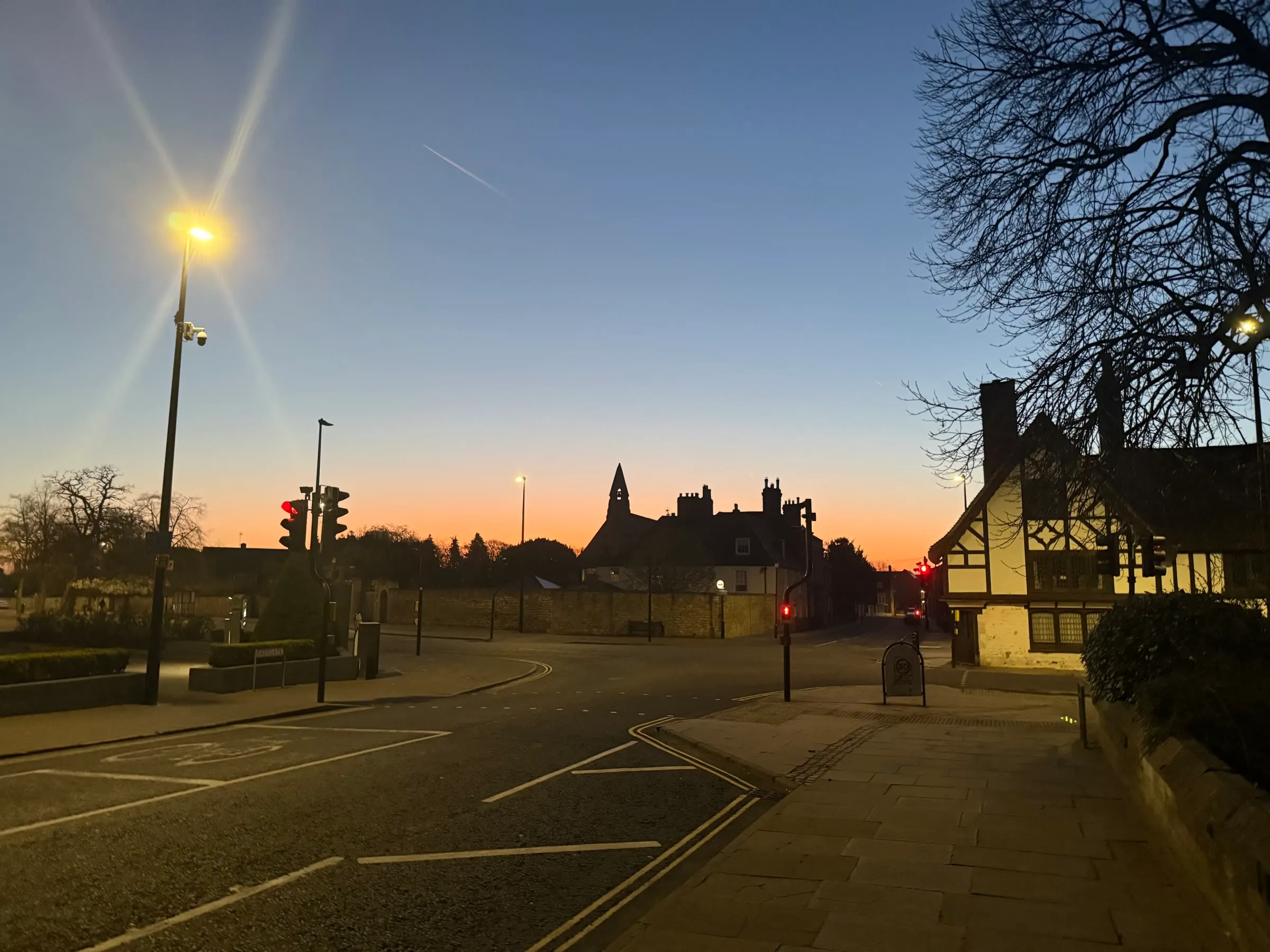 A quiet junction in Lincoln before dawn, with silhouetted buildings beneath a blue and amber sky