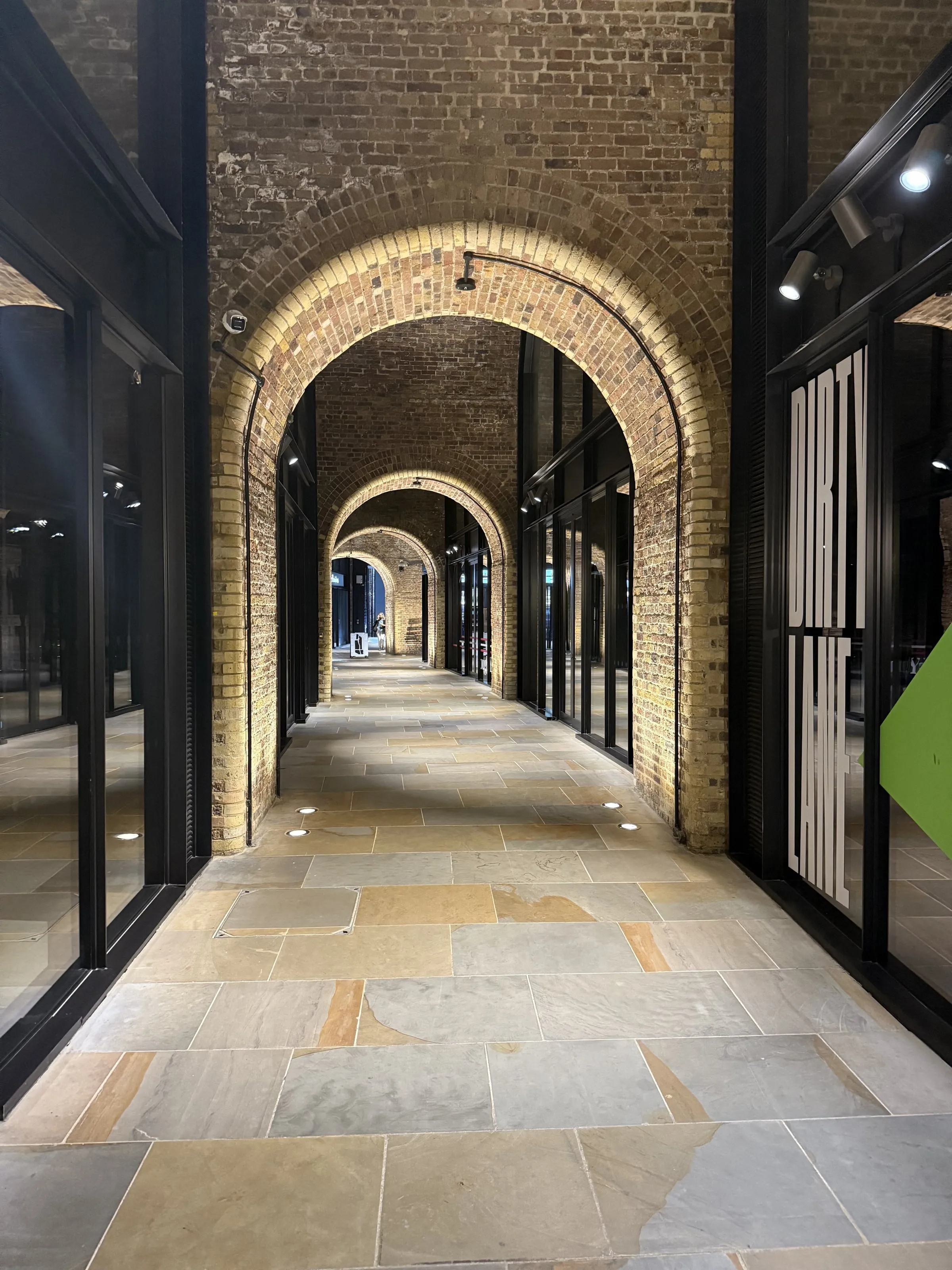 An empty brick arcade, its arches lit from within, running away into the distance