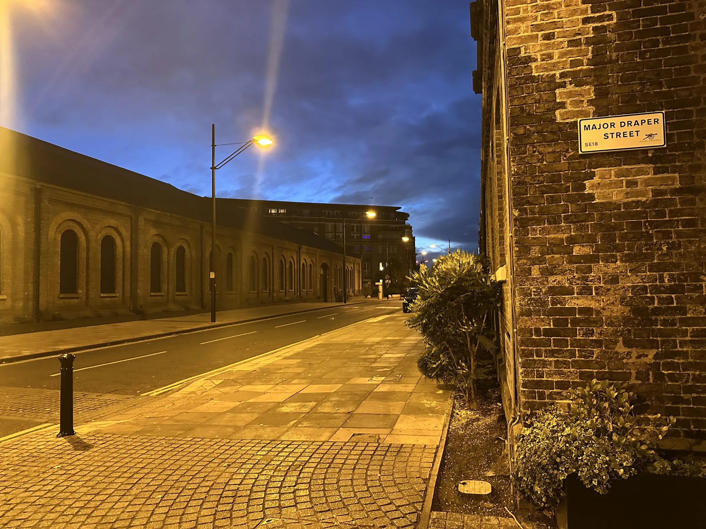 The long brick gun factories of Woolwich under street lamps, the sky a steely dark blue
